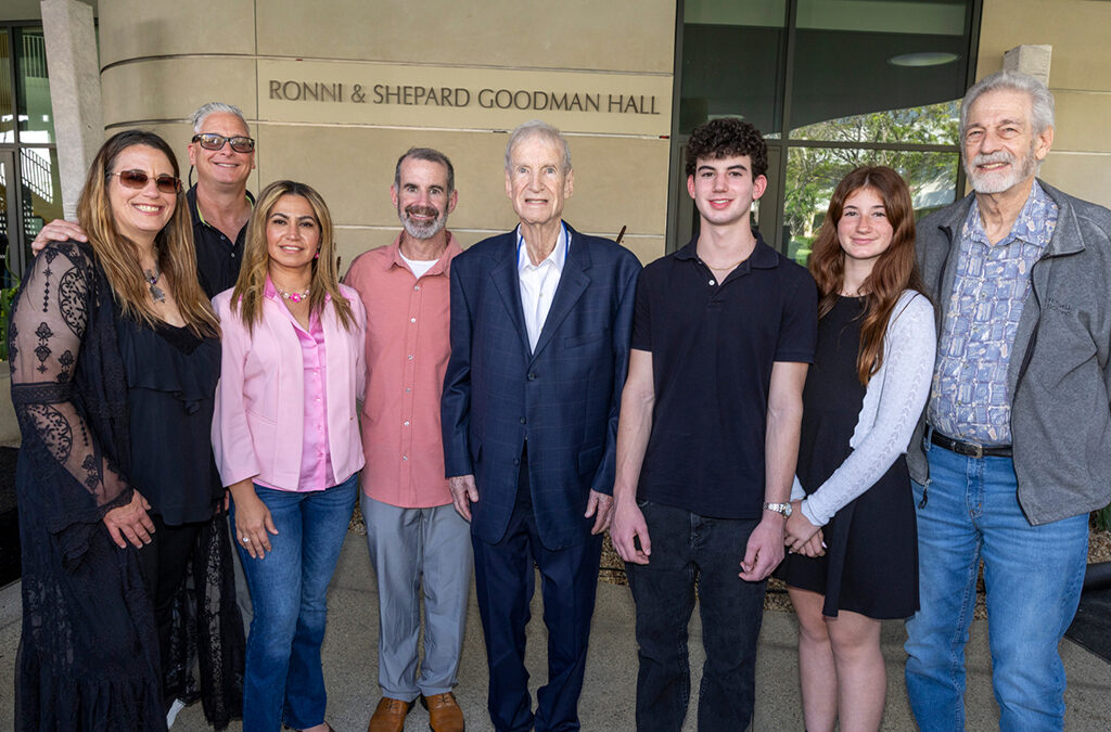 A well-dressed family poses in front of a building that honors their family. 