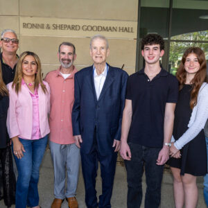 A well-dressed family poses in front of a building that honors their family.