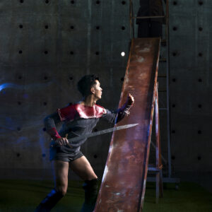 Actors dressed as Flash Gordon and Ming the Merciless confront each other on a playground slide.