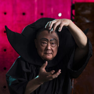 Bruce Yonemoto in a black tunic and collar as Flash Gordon villain Ming the Merciless.