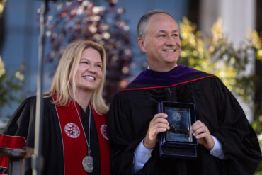 CSUN President Erika D. Beck and Doug Emhoff stand together on stage. Emhoff holds a glass plaque.