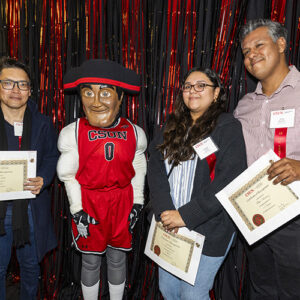 Three people holding certificates stand with Matty the Matador.