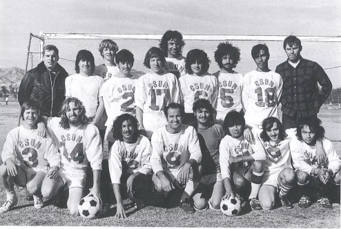 Black-and-white photo of CSUN men's club soccer team, wearing uniforms and lined up in two rows in front of a soccer goal.