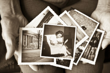 Elderly woman holding a collection of old photographs