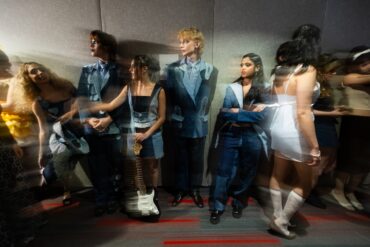 A motion blurred image of models in line at a fashion show.