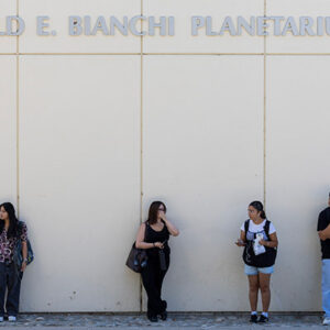 Students stand against a white building, below a sign that says Donald E. Bianchi Planetarium.
