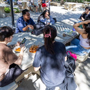 Five students seated around concrete table.