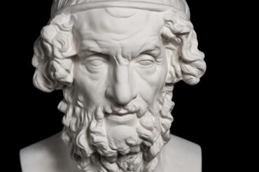 White gypsum copy of ancient statue of Homer head for artists isolated on a black background. Plaster sculpture of man face.