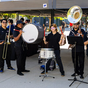 Students dressed in black stand outside with their instruments.