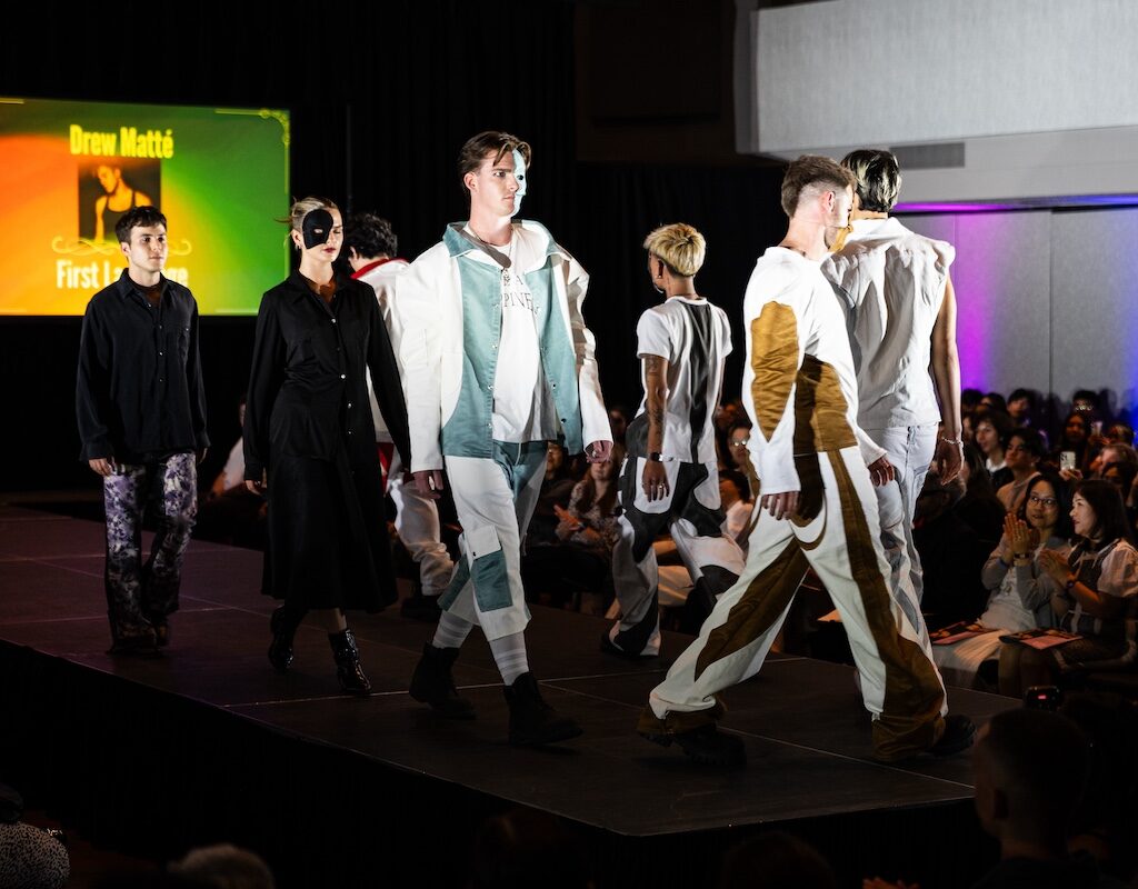 Models wearing white and dark menswear luxury streetwear on a fashion runway.