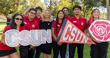 CSUN President Erika D. Beck stands with a group of students who are holding CSUN signs.