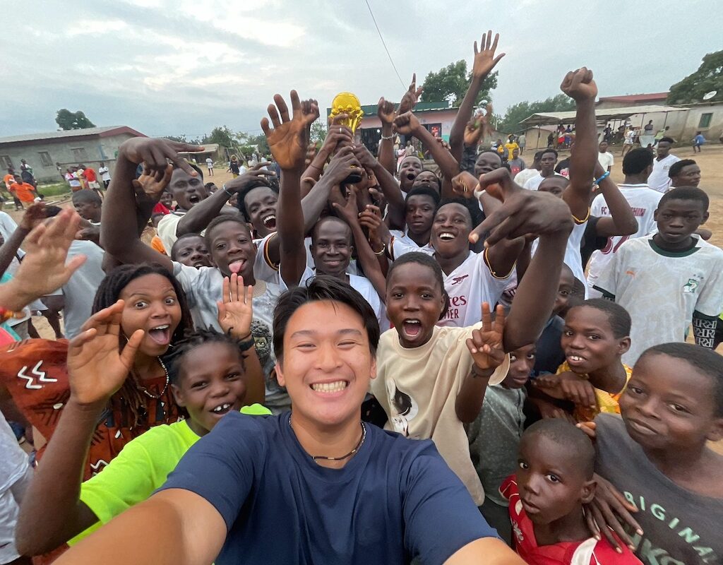 A CSUN student and professor taking a joyous group shot with dozens of people in Côte d’Ivoire.