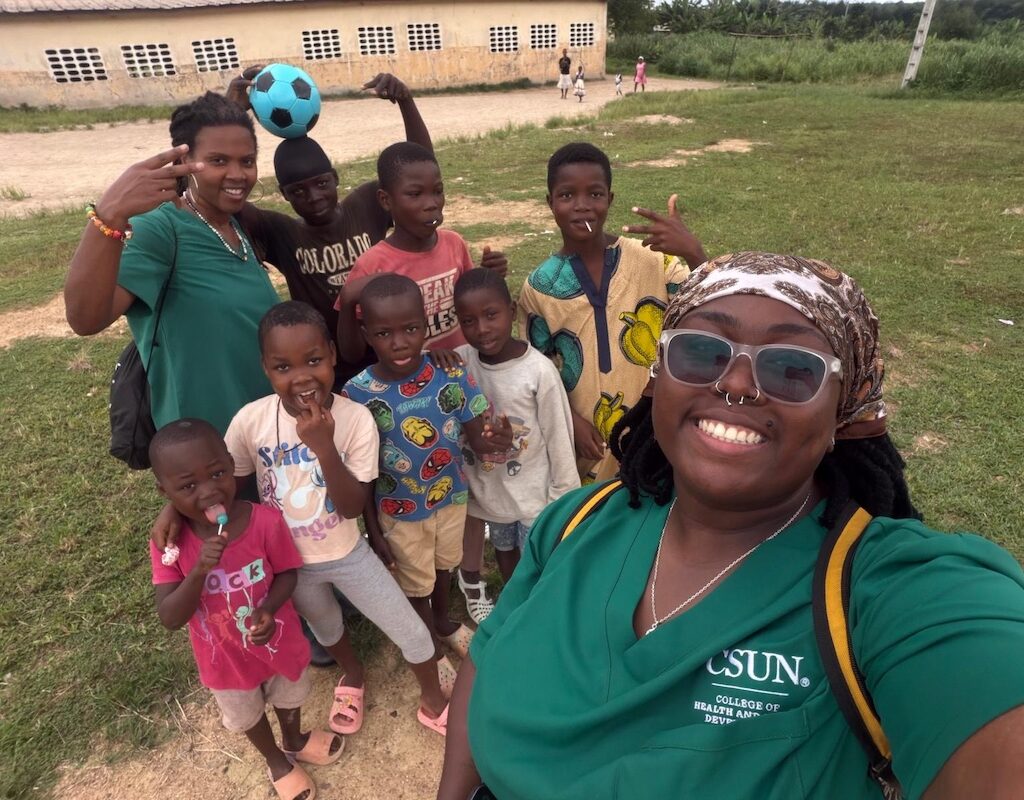 A CSUN student and professor pose for a group photo with young villagers in Cote d'Ivoire.