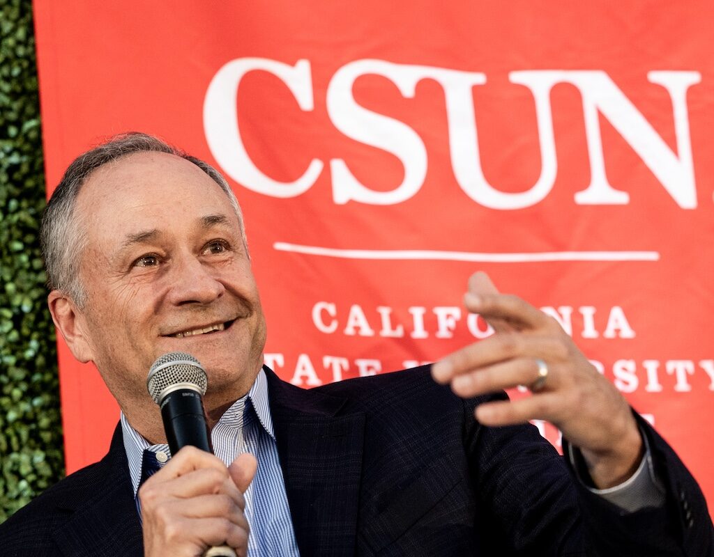 Former Second Gentleman Doug Emhoff speaks into a microphone in front of a CSUN banner. 