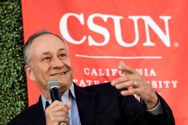 Former Second Gentleman Doug Emhoff speaks into a microphone in front of a CSUN banner.
