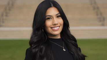 A female student poses for a portrait in front of the University Library steps.